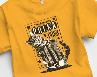 May include: A yellow t-shirt with a black and white illustration of a cat playing an accordion. The text "The Amazing Polka Puss" is printed on the shirt.