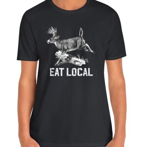 May include: Black t-shirt with a white illustration of a deer jumping over a log. The text "EAT LOCAL" is printed below the deer.