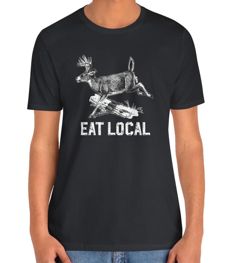 May include: Black t-shirt with a white illustration of a deer jumping over a log. The text "EAT LOCAL" is printed below the deer.
