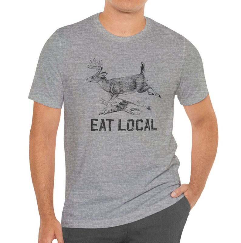 May include: A heather grey t-shirt with a black and white illustration of a deer running. The text "EAT LOCAL" is printed below the deer.