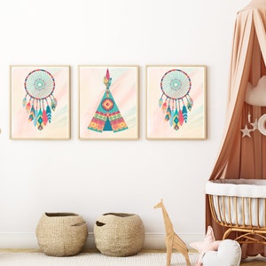 Puede incluir: Tres impresiones enmarcadas con un tema boho. Las impresiones presentan un tipi, un atrapasueños y plumas. Las impresiones están en una pared blanca en una guardería.