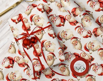 May include: Christmas-themed wrapping paper featuring a repeating pattern of Santa Claus illustrations in red and white. A wrapped gift is adorned with a red ribbon and ornaments. A roll of matching paper and gold scissors are also visible.