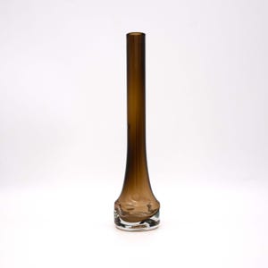 Könnte beinhalten: Eine hohe, schlanke braune Glasvase mit einem klaren Glasfuß. Die Vase hat eine abgerundete, bauchige Form am Boden und eine schmale Öffnung oben.