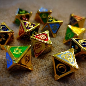 May include: A collection of gold-colored, geometric dice with various colorful symbols and designs on each face. The dice have a metallic sheen and are arranged on a textured surface, showcasing a variety of colors including blue, green, red, and gold.