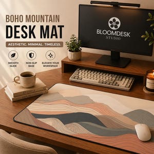 Pode incluir: Um tapete de secretária retangular com uma paisagem impressa de montanhas em camadas em tons de bege, terracota e cinzento escuro com detalhes de linhas finas. O tapete está posicionado numa secretária de madeira com monitor, teclado e rato.