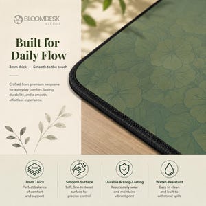 May include: A rectangular desk mat featuring a dark green surface with a repeating floral line art pattern and black stitched edges. The mat is 3mm thick and includes text stating Built for Daily Flow, 3mm thick, and Smooth to the touch.