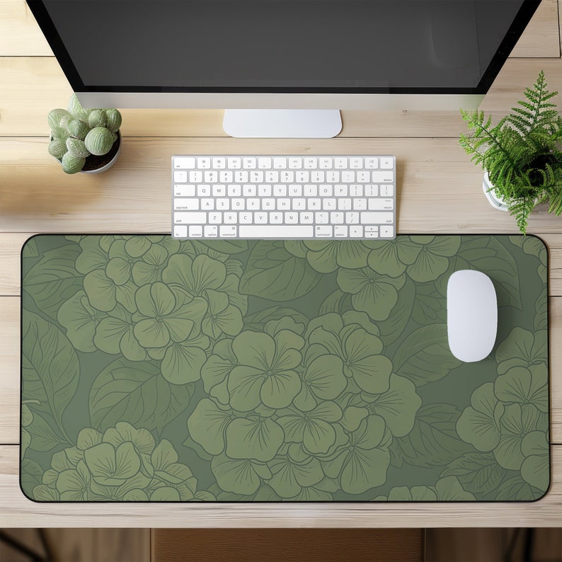 May include: A green floral mousepad with a white computer mouse on top of it. The mousepad has a pattern of green hydrangea flowers on a green background.