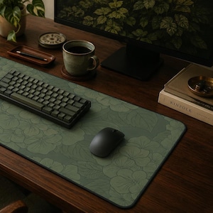 May include: A rectangular desk mat featuring a dark olive green surface with a repeating line art pattern of hydrangea flowers and leaves. The mat has a black stitched edge and is positioned under a black mechanical keyboard and a black computer mouse.