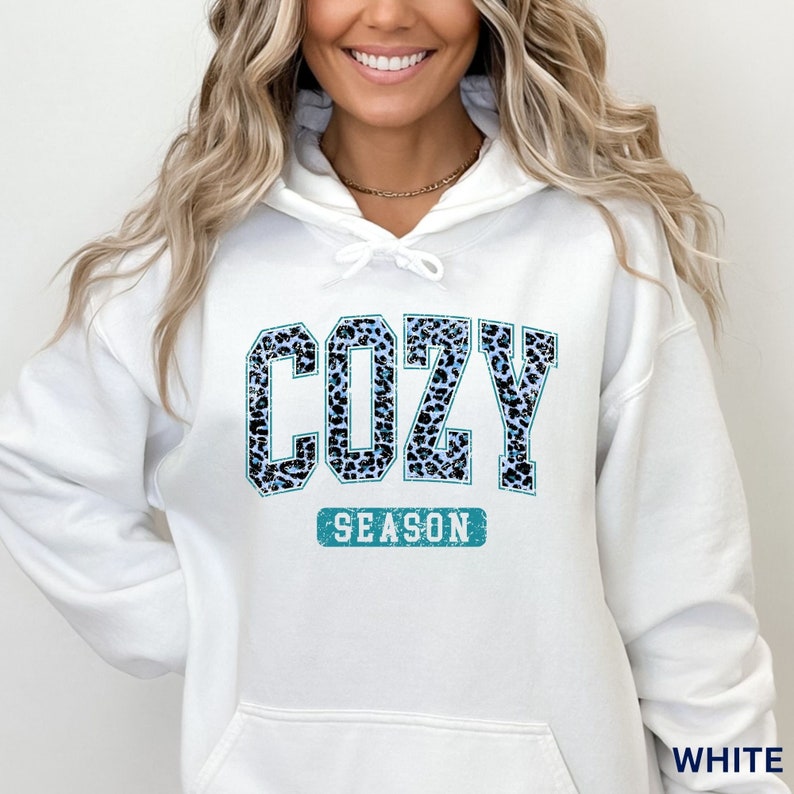 May include: White hooded sweatshirt with a blue and black leopard print graphic that says "Cozy Season".