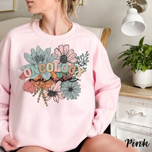 May include: Pink sweatshirt with a floral design and the text "ONCOLOGY nurse" in colorful letters.
