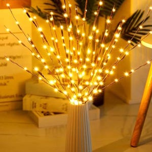 May include: A set of twig-like branches with warm white LED lights, arranged in a vase. The lights create a warm, inviting glow.