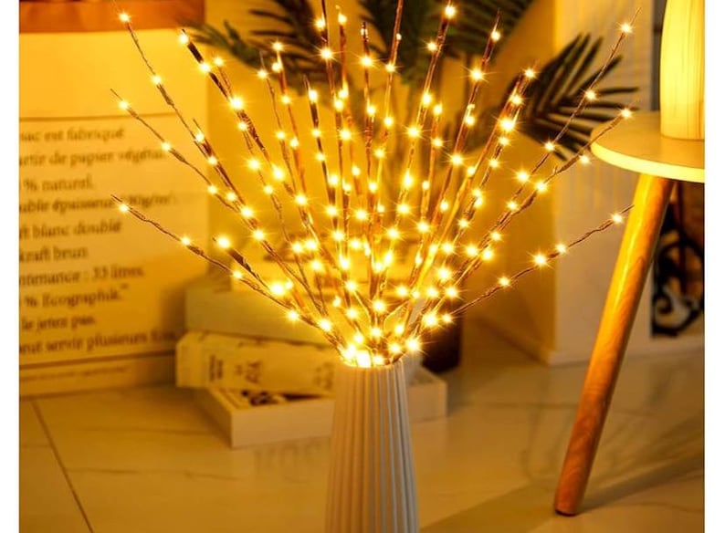 May include: A set of twig-like branches with warm white LED lights, arranged in a vase. The lights create a warm, inviting glow.