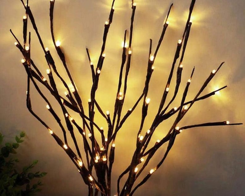 May include: A set of twig-like branches with warm white LED lights strung along them. The branches are arranged in a vase-like shape, creating a decorative and festive ambiance.