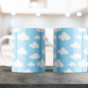 Puede incluir: Dos tazas de cerámica blanca con un patrón de nubes azules y blancas. Las tazas tienen asas blancas.