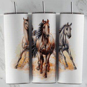 Può includere: Un set di tre bicchieri isolanti bianchi con un'illustrazione ad acquerello di cavalli in corsa. I cavalli sono raffigurati in tonalità di marrone, grigio e beige, con criniere e code fluenti. Ogni bicchiere ha una cannuccia color argento e un coperchio nero.