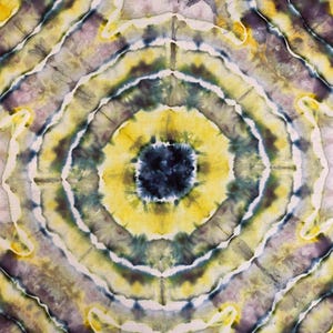 Może przedstawiać: Tekstylny tie-dye z okrągłym wzorem. Wzór składa się z koncentrycznych pierścieni w kolorze żółtym, niebieskim, fioletowym i białym. Środek to ciemnoniebieskie koło. Całość tworzy psychodeliczny, artystyczny design.