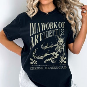 Pu&ograve; includere: Maglietta nera con una grafica di uno scheletro in fiamme e il testo "IMA WORK OF ARTHRITIS CHRONIC ILLNESS CLUB".