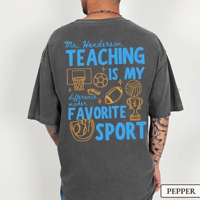 May include: Dark gray t-shirt with the text "Mr. Henderson TEACHING IS MY FAVORITE SPORT" in blue and gold. The design includes illustrations of a basketball hoop, soccer ball, football, volleyball, trophy, and baseball glove.