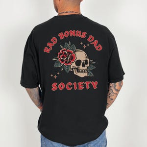 May include: Black t-shirt with a red skull and rose graphic and the text "Rad Bonus Dad Society" printed on the back.