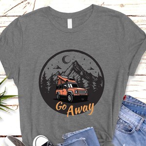 May include: Gray t-shirt with a graphic of a camper van in a mountain landscape with the text "Go Away".