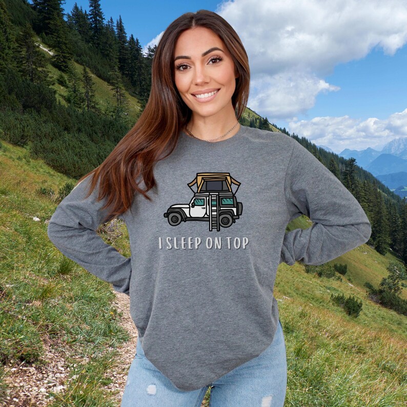 May include: A gray long-sleeved shirt with a cartoon illustration of a car with a tent on top. The text "I SLEEP ON TOP" is printed below the illustration.