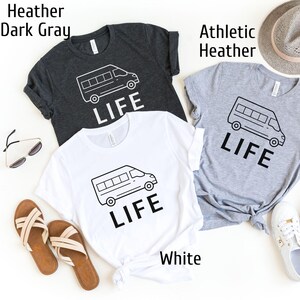Op de afbeelding: Drie T-shirts met een afbeelding van een busje en het woord "LIFE" erop gedrukt. De T-shirts zijn in wit, donkergrijs melange en sportgrijs melange.