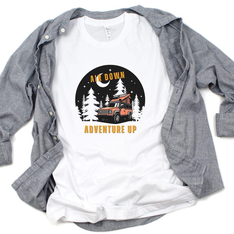Puede incluir: Camiseta blanca con un gr&aacute;fico de un coche en un bosque de noche con el texto "Air Down Adventure Up".
