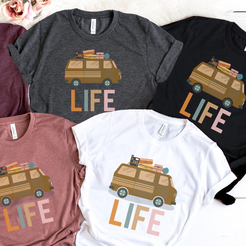May include: A collection of t-shirts in various colors, each featuring a brown van graphic with luggage and the word "LIFE" in colorful letters. The shirts are made of a soft material.