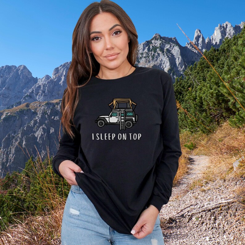 May include: A black long-sleeved shirt with a white Jeep with a tent on top and the text "I SLEEP ON TOP".