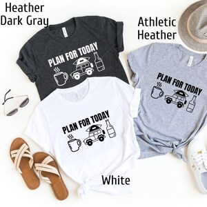 May include: Three t-shirts in different colors: dark gray, white, and athletic heather. Each shirt features a black and white graphic of a car with a tent on top, a coffee cup, and a beer bottle. The text "PLAN FOR TODAY" is printed on each shirt.