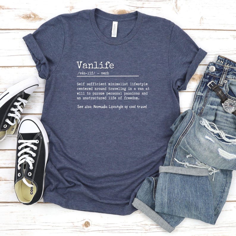 Puede incluir: Una camiseta azul marino con el texto "Vanlife /van-lif/ verbo Estilo de vida minimalista autosuficiente centrado en viajar en una furgoneta a voluntad para perseguir pasiones personales y una vida no estructurada de libertad. Ver tambi&eacute;n: Estilo de vida n&oacute;mada de viajes geniales" impreso en la parte delantera.