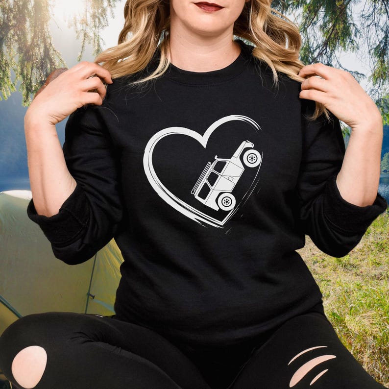 May include: Black long-sleeve sweatshirt featuring a white heart design with a white off-road vehicle graphic inside. The sweatshirt is made of a soft material and is suitable for casual wear. The design is simple and eye-catching.