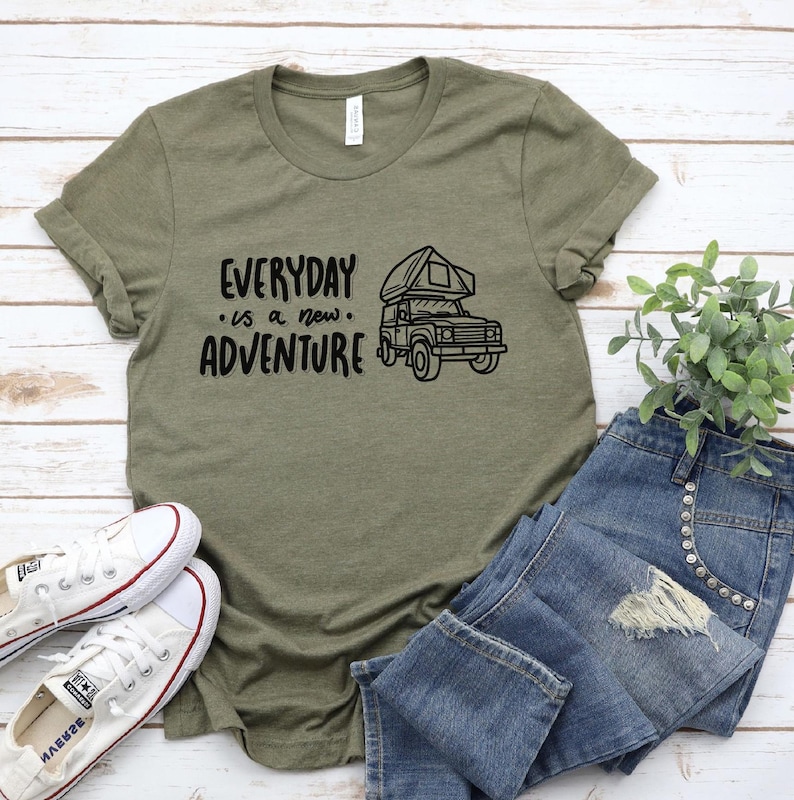May include: A green t-shirt with the text "EVERYDAY is a new ADVENTURE" and a black and white illustration of a camper van with a pop-up roof.