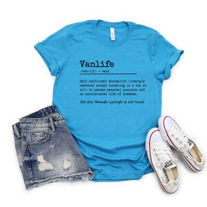 Puede incluir: Una camiseta azul turquesa con la palabra "Vanlife" definida como "Estilo de vida minimalista autosuficiente centrado en viajar en una furgoneta a voluntad para perseguir pasiones personales y una vida no estructurada de libertad. Ver tambi&eacute;n: Estilo de vida n&oacute;mada de viajes geniales."