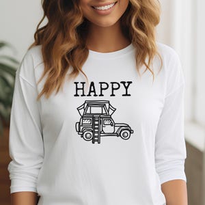 May include: White long-sleeve shirt with the word "HAPPY" printed in black above a black and white illustration of a car with a tent on top.