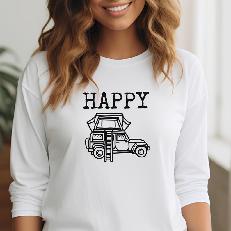 May include: White long-sleeve shirt with the word "HAPPY" printed in black above a black and white illustration of a car with a tent on top.