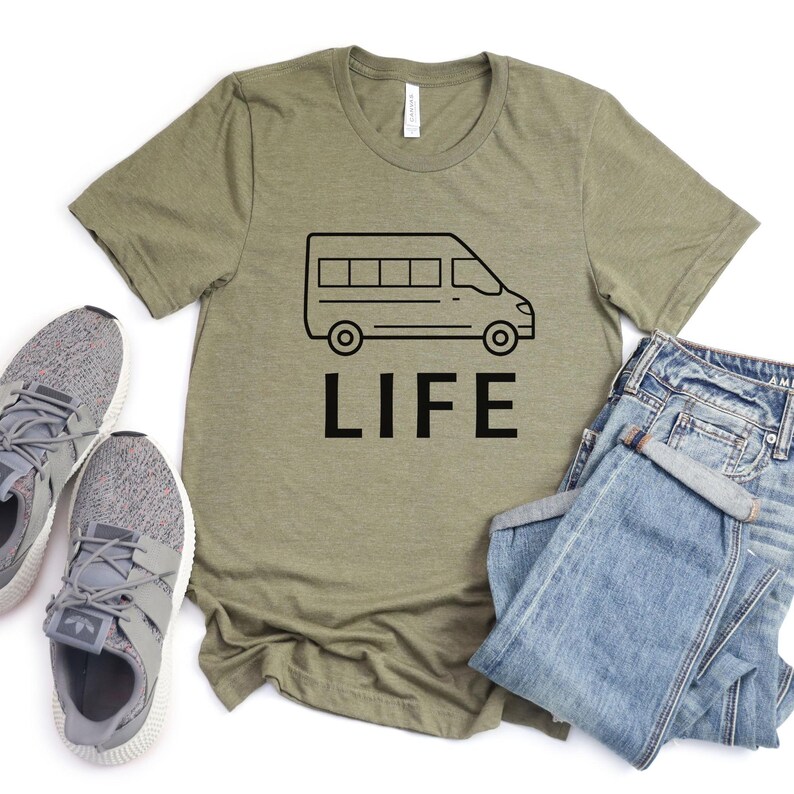 Op de afbeelding: Een groen T-shirt met een zwarte omtrek van een bestelwagen en het woord "LIFE" erop gedrukt.