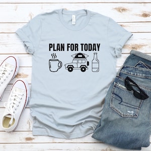 May include: Light blue t-shirt with the text "PLAN FOR TODAY" in black. The design includes a coffee mug, a jeep with a tent on top, and a bottle of beer.