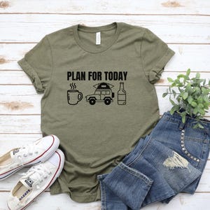 Puede incluir: Camiseta verde oliva con la frase "PLAN FOR TODAY" e iconos gr&aacute;ficos de una taza de caf&eacute;, un veh&iacute;culo de camping y una botella. La camiseta se combina con vaqueros azules y zapatillas blancas.