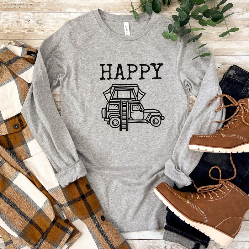 May include: Gray long-sleeve shirt with the text "HAPPY" and a black and white illustration of a car with a tent on top.