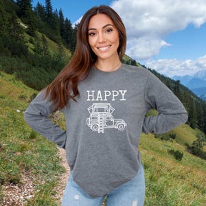 May include: Gray long-sleeve shirt with the word "HAPPY" and a white outline of a car with a tent on top. The car has a ladder on the side.