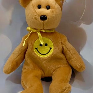 May include: A set of three ceramic mugs with a speckled, matte finish. The mugs are in shades of cream, light gray, and dark gray. Each mug has a simple, minimalist design and a rounded handle.