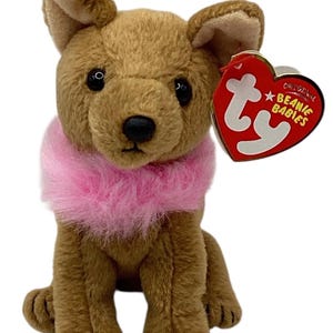 May include: A brown plush dog toy with a pink collar. The toy has black eyes and a black nose. A red heart-shaped tag with the words "Original Beanie Babies" is attached to the toy.