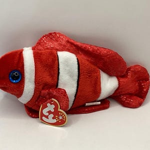 May include: Red and white plush clownfish with a blue eye and a Ty Beanie Baby tag.