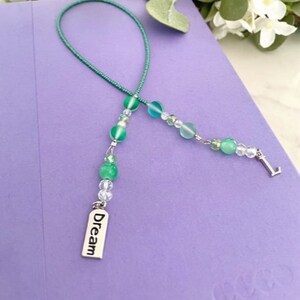 May include: A green beaded bookmark with a silver charm that says "Dream".