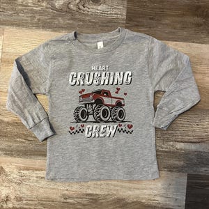 May include: Gray long-sleeve shirt with a red truck graphic and the text "Heart Crushing Crew".