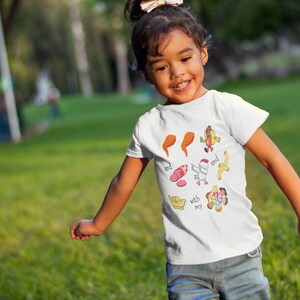 May include: A white t-shirt with a colorful graphic design featuring a chicken, a hot dog, a banana, a sausage, and a group of people. The text on the shirt reads "with my and and".