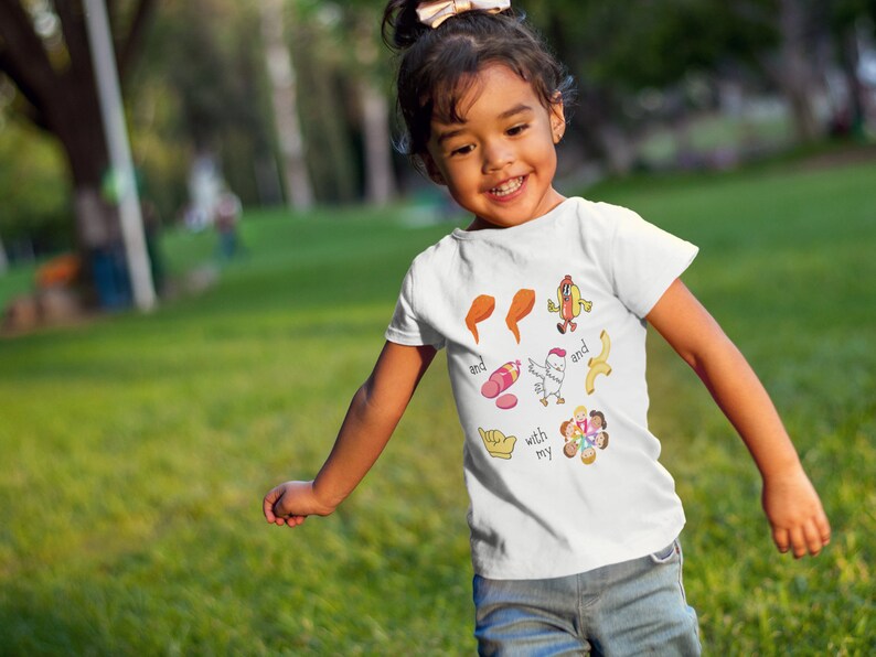 May include: A white t-shirt with a colorful graphic design featuring a chicken, a hot dog, a banana, a sausage, and a group of people. The text on the shirt reads "with my and and".
