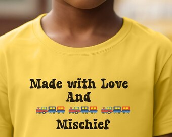 May include: A young boy wearing sunglasses and a yellow t-shirt with the text "Made with Love And Mischief" and a line of toy train images.