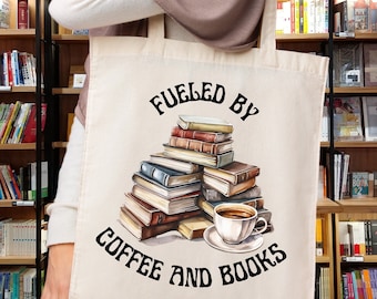 May include: A white canvas tote bag with the text "Fueled by Coffee and Books" in black. A stack of books and a cup of coffee are depicted in the center of the bag.